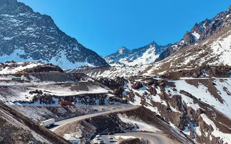 Vista de dentro da cadeirinha do teleférico de Portillo, com a estrada em curvas e os picos nevados embaixo