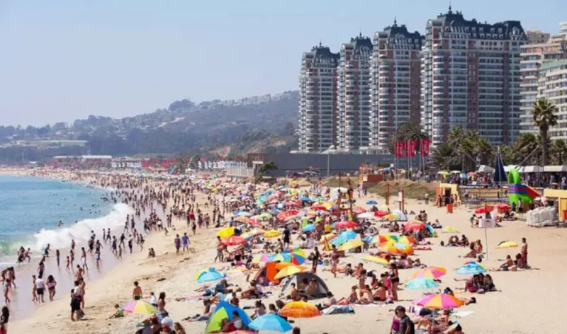 Praia de Viña del Mar lotada de guarda-sóis no verão, com os prédios da orla ao fundo