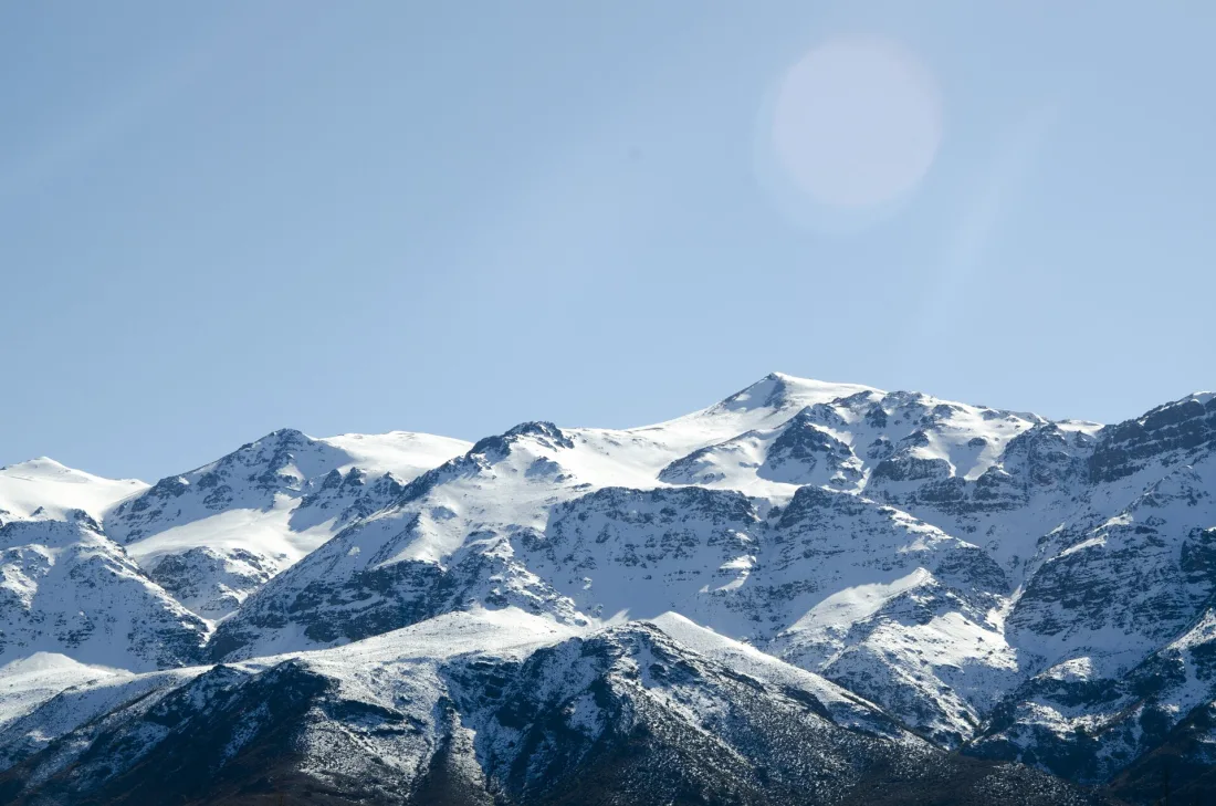 Cadeia de picos da Cordilheira dos Andes cobertos de neve sob um céu azul claro